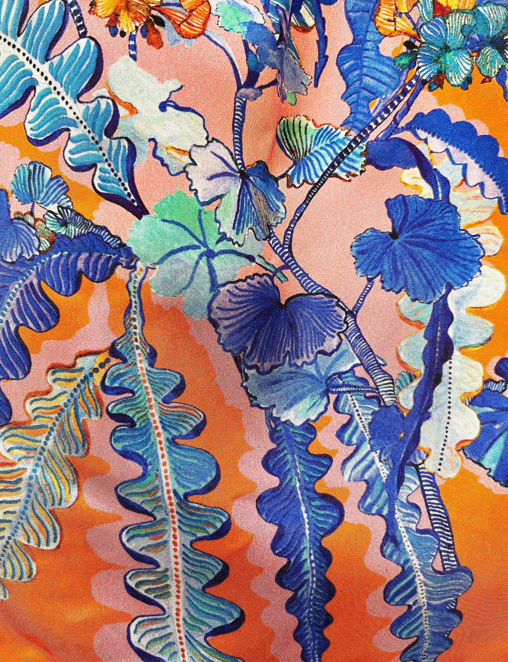 Eleni Malami luxury silk handbag with orange and cobalt geranium floral design and elegant fringe detailing.
